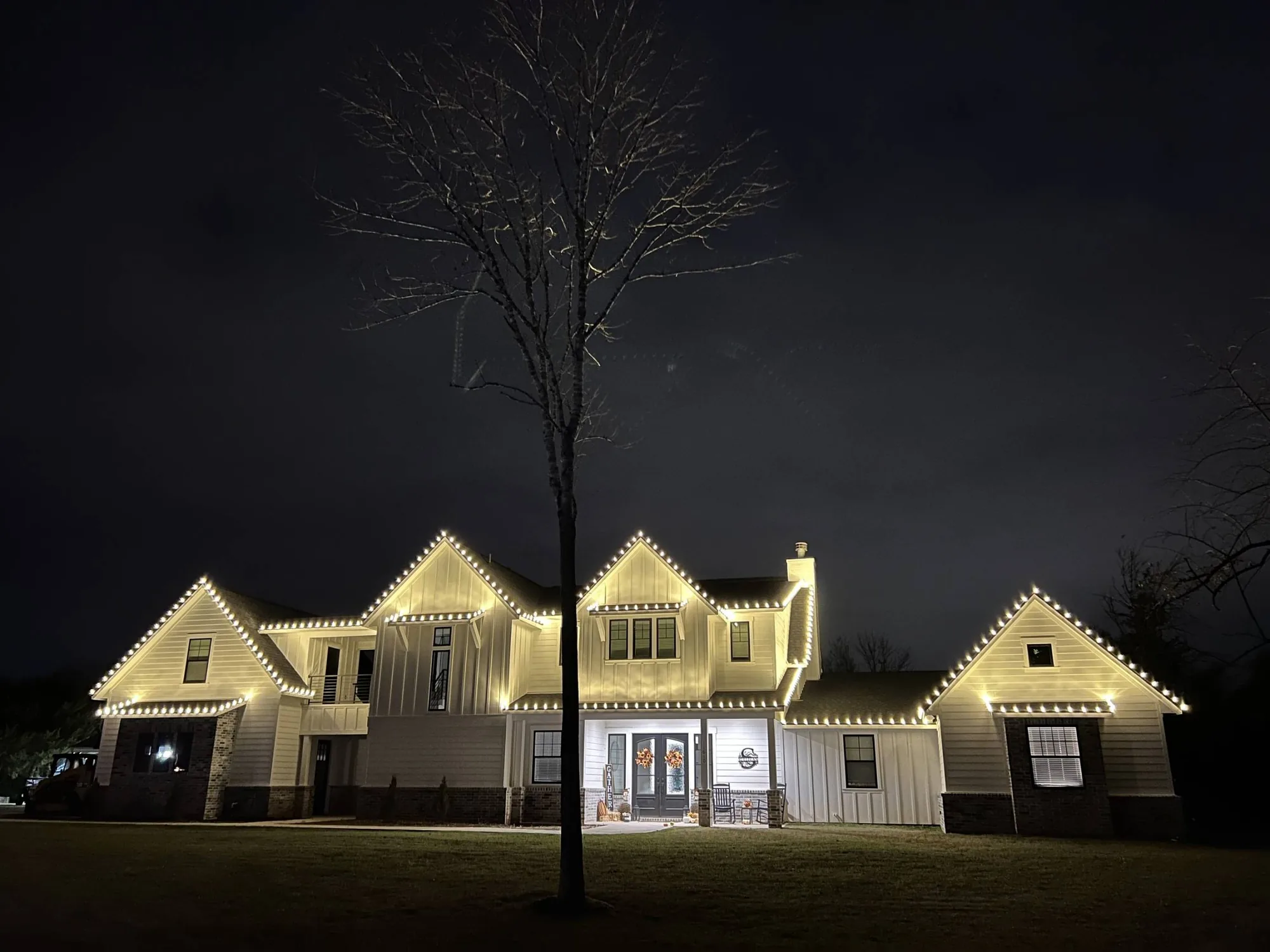 A large Texas estate at night, every gable, dormer and roofline traced in warm-white holiday lighting.